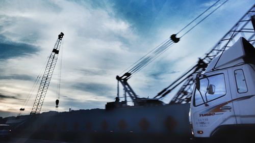 Low angle view of cranes against sky