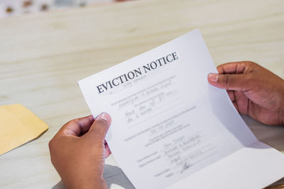 Cropped image of man holding book with text on table
