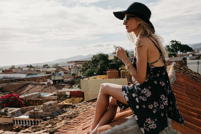 Side view of woman sitting against built structure