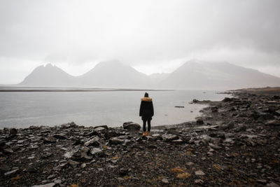 Rear view of man standing on mountain against sky