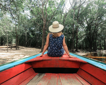 Rear view of woman sitting by plants against trees