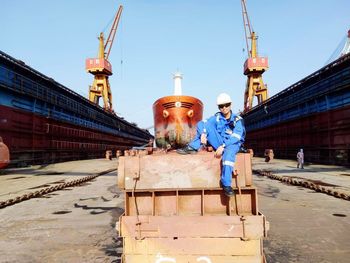 Portrait of smiling worker sitting on machinery at commercial dock
