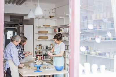 Female potters standing by table working in ceramics workshop