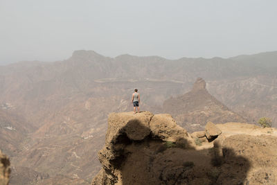 Man standing on rocky mountain against sky