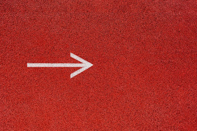 Directly above shot of arrow sign on red floor