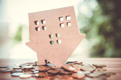 Close-up of model house on coins at table