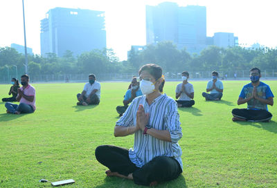 People sitting on field against buildings