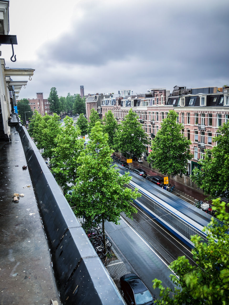 HIGH ANGLE VIEW OF ROAD AMIDST TREES AND BUILDINGS IN CITY