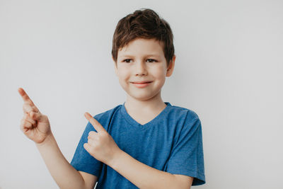 A preschool boy in a blue t-shirt on a light background shows a thumbs up. high quality photo