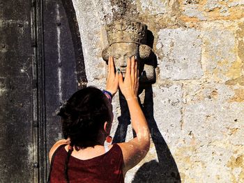 Rear view of women touching sculpture on wall