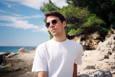 Portrait of young man wearing sunglasses standing on land