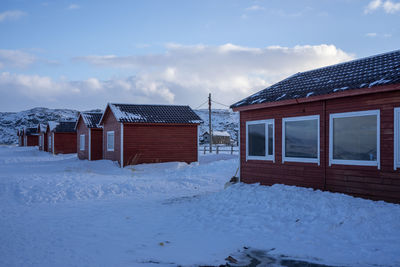 House on snow covered field against sky