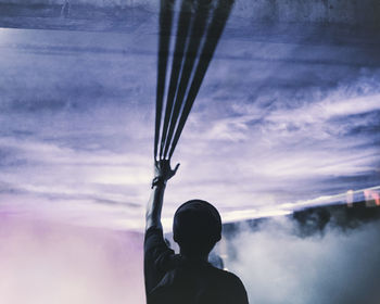 Rear view of man with arm raised while standing in foggy room