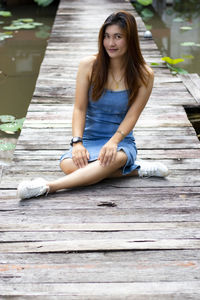 Portrait of a young woman sitting on wood