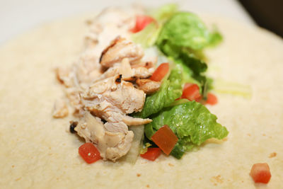 Chicken and turkey mixed with chopped lettuce and tomato on a wrap