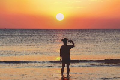 Silhouette man standing at beach during sunset