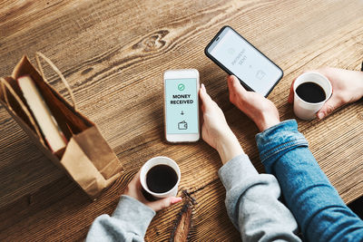 Low section of woman using mobile phone on table
