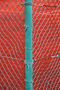 Close-up of metal fence against brick wall