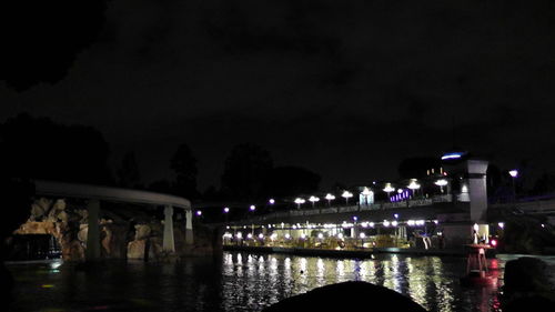 Illuminated bridge over river against sky at night