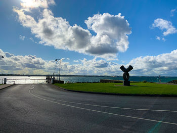 Man standing on road against cloudy sky