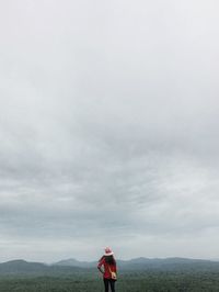 Rear view of woman standing against cloudy sky