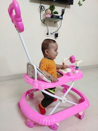 Cute girl holding toy while sitting on floor