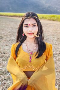 Portrait of beautiful young woman standing on field