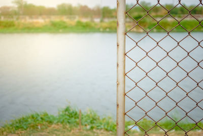 Close-up of fence against lake