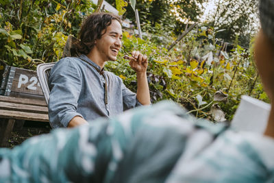 Happy man having food sitting with female volunteer in garden