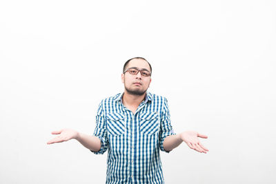 Portrait of confused man gesturing while standing against white background