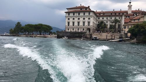 View of buildings by sea against cloudy sky