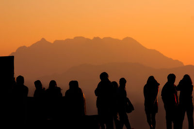 Silhouette people standing against mountains during sunset