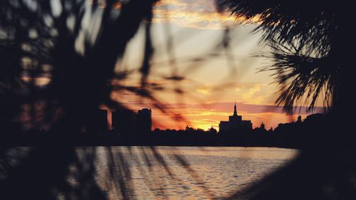 Silhouette of buildings against cloudy sky during sunset