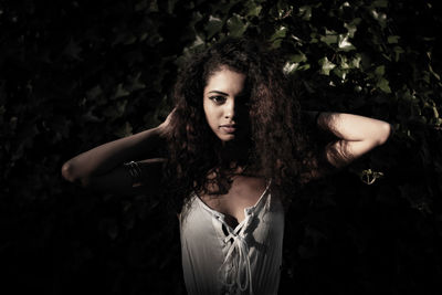 Portrait of beautiful young woman standing against tree