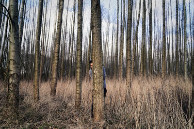 Man hiding behind tree in forest