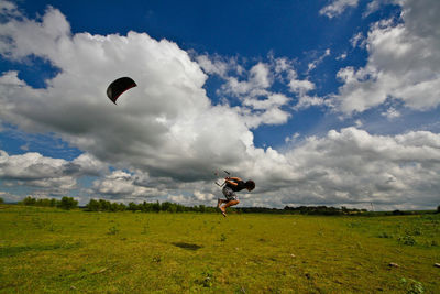 Man paragliding over field against sky