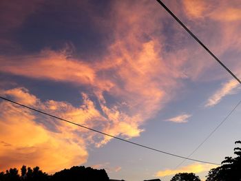 Low angle view of silhouette power lines against sky during sunset
