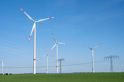 Windmills on field against sky