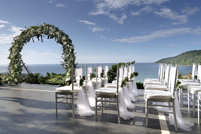 Chairs and table at beach against sky