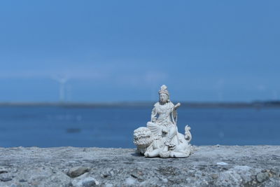 Statue on rock by sea against sky