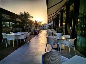 Empty chairs and tables in restaurant at sunset