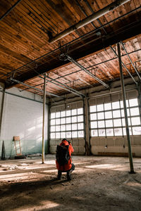 Young man with backpack crouching in abandoned room