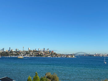 City at waterfront against blue sky