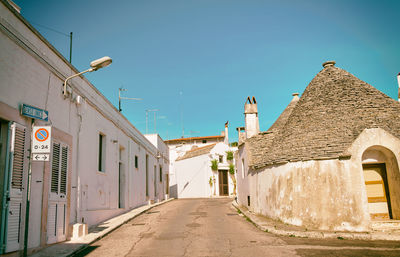 Street amidst buildings against clear blue sky