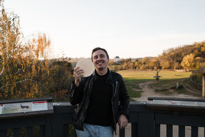 Portrait of smiling young man standing against sky