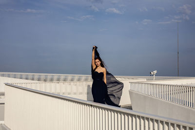 Woman standing by railing against sky