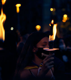 Portrait of woman holding lit candles at night