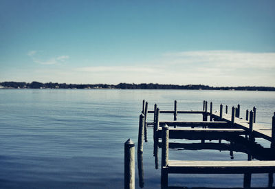 Pier in river against sky on sunny day