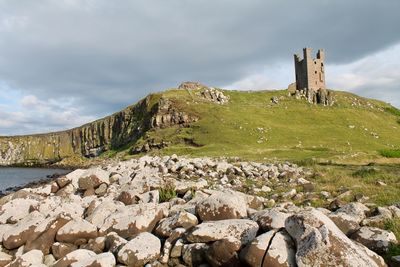 Stone wall by rocks against sky