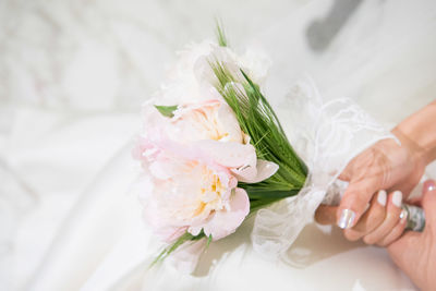 Midsection of bride holding rose bouquet